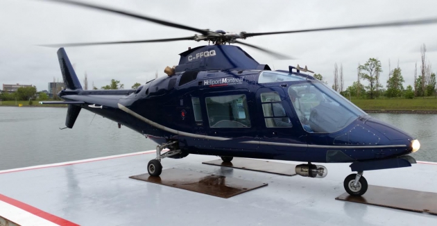 Un hélicoptère bleu est posé sur un quai à côté d’un plan d’eau et fournit des services essentiels.