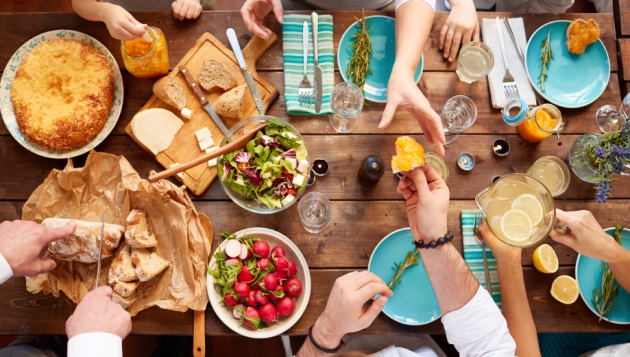 Un groupe de personnes assises autour d'une table avec de la nourriture, profitant de leur alimentation ensemble.