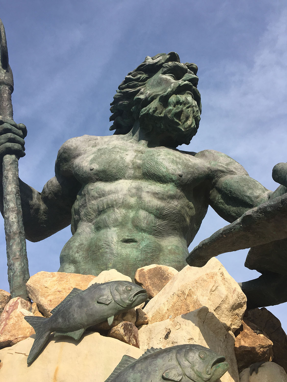 Une statue d'un homme avec une lance et un poisson.