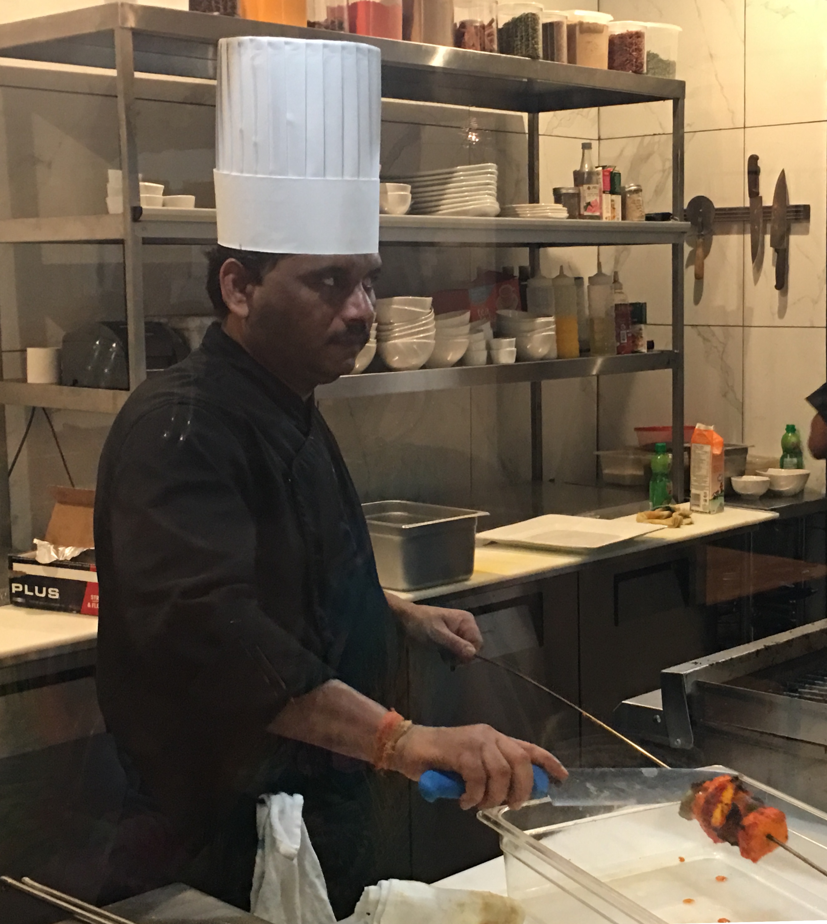 Un homme en toque prépare une cuisine raffinée dans une cuisine.