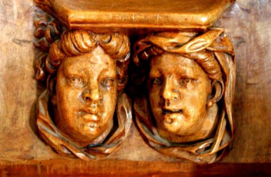 Une sculpture de deux visages sur une étagère en bois, déguster