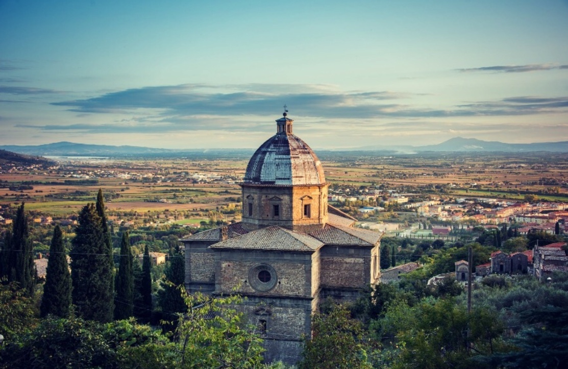 Une église au sommet d'une colline surplombant une vallée avec une touche de Santa Cristina.