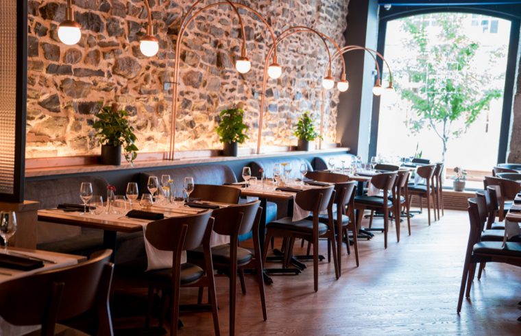 Chez L'Épicier, un restaurant avec mur de pierre et tables en bois.