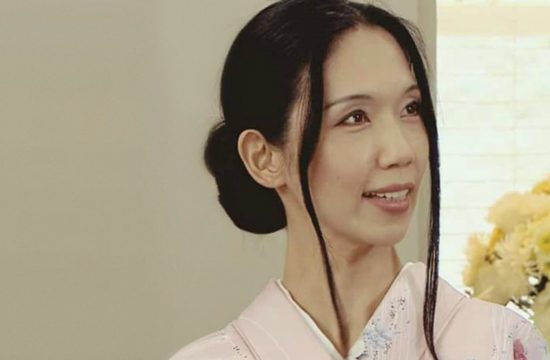 Kuniko Fujita, sommelière de saké, sourit dans un kimono rose lors d'une interview.