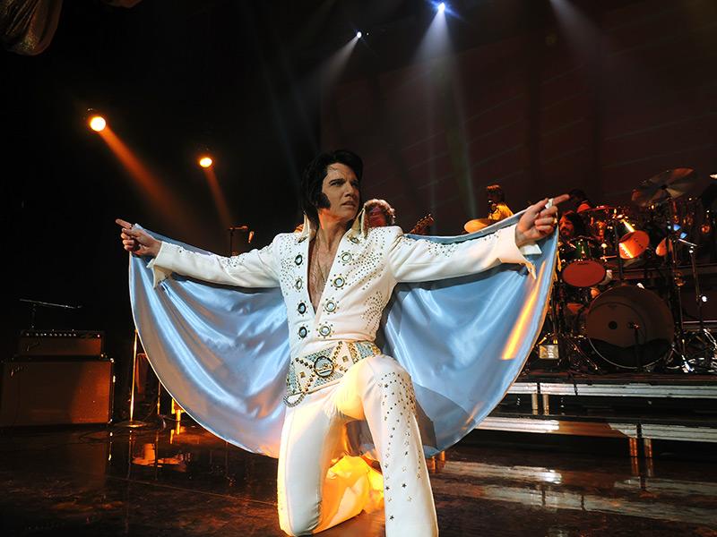 Elvis Presley se produit sur scène à Montréal les bras tendus.