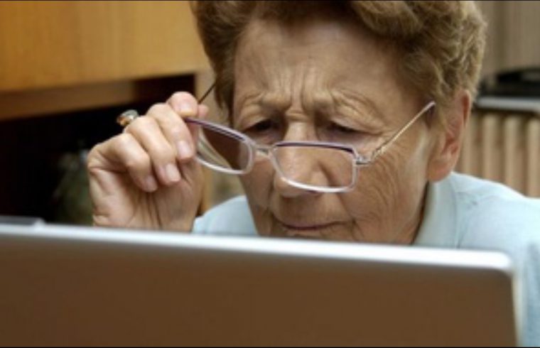 Une femme âgée navigue sur Internet sur un ordinateur portable.