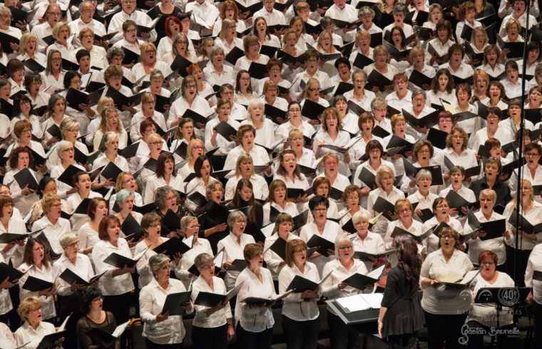 Un grand groupe de personnes en chemise blanche chantant le chant Québec.