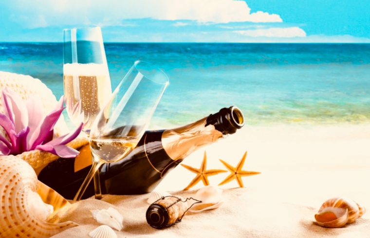 Une bouteille de champagne et des coquillages sur la plage pendant l'été.