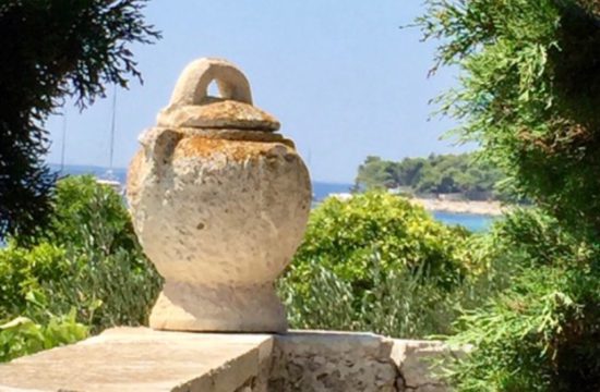 Une urne en pierre se trouve sur un charmant mur de pierre près de l'océan en Croatie.