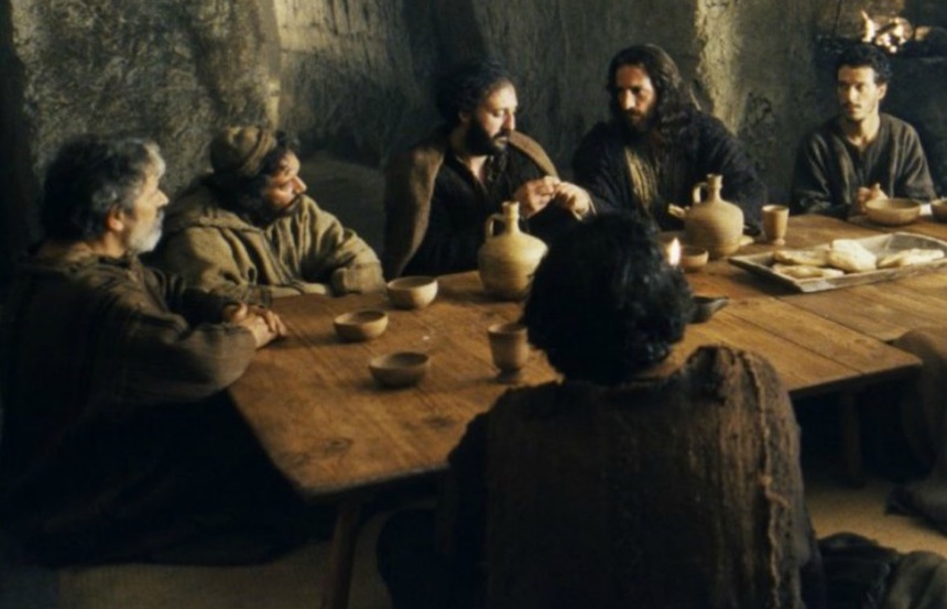 Un groupe de personnes, dont Jésus, assis autour d'une table dans une grotte.