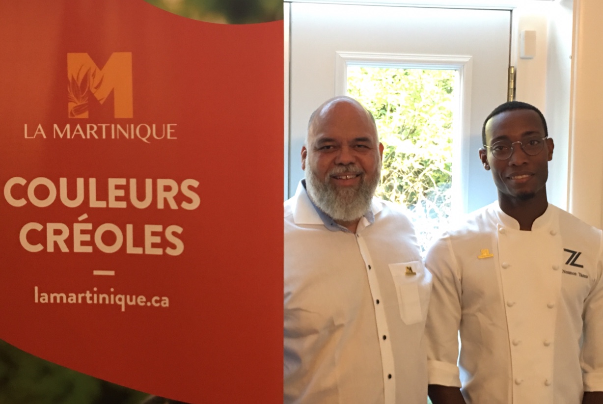 Deux chefs debout devant une pancarte indiquant couloirs créoles lors d'un festival culinaire en Martinique.