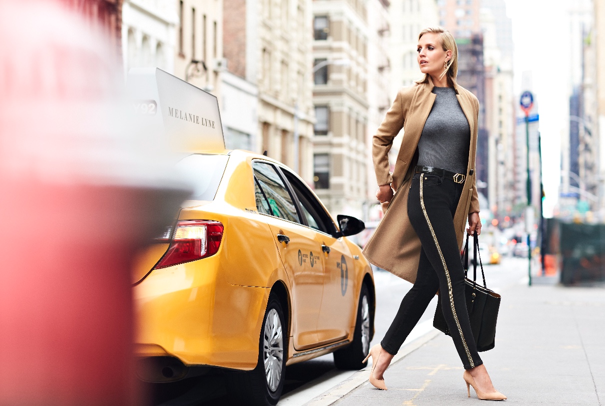 Mélanie Lyne, une femme marchant dans une rue de la ville avec un taxi en arrière-plan.