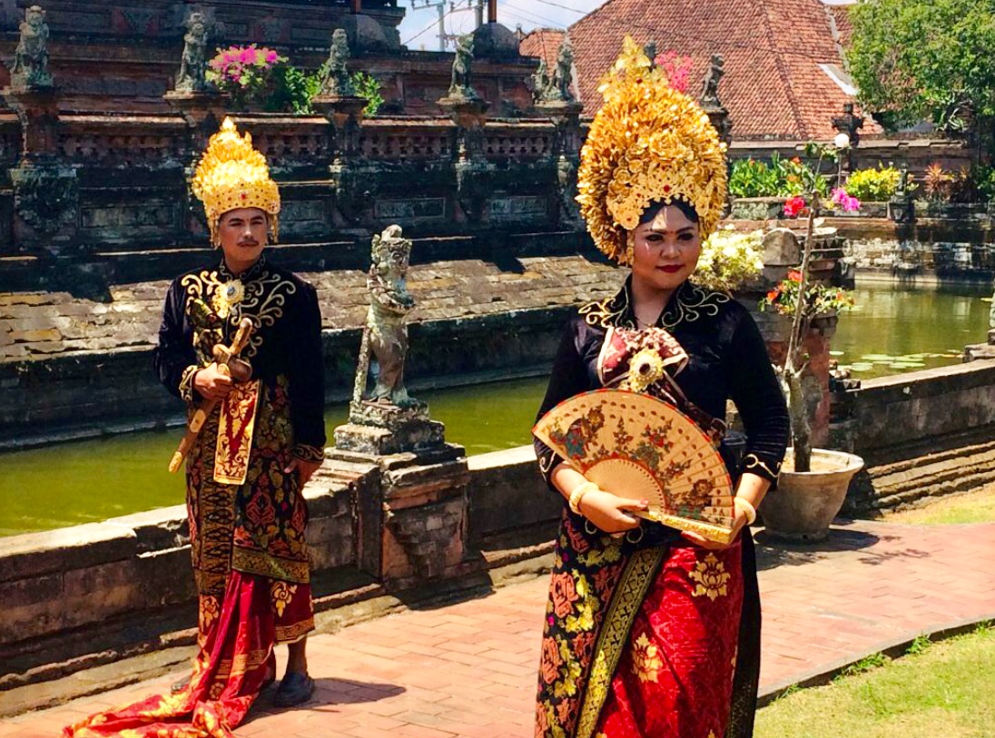 Deux femmes en costumes traditionnels de Bali debout à côté d'un étang.