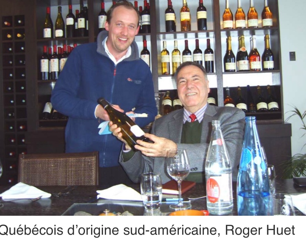 Roger Huet et Roger Hudson attablés avec une bouteille de vin.