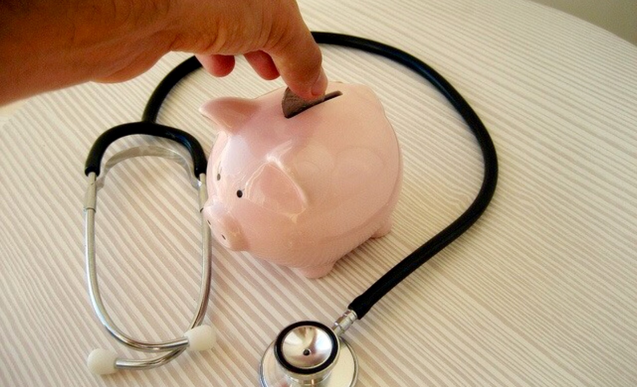 Une tirelire rose avec un stéthoscope à côté, représentant l'importance de la santé et du bien-être financier.