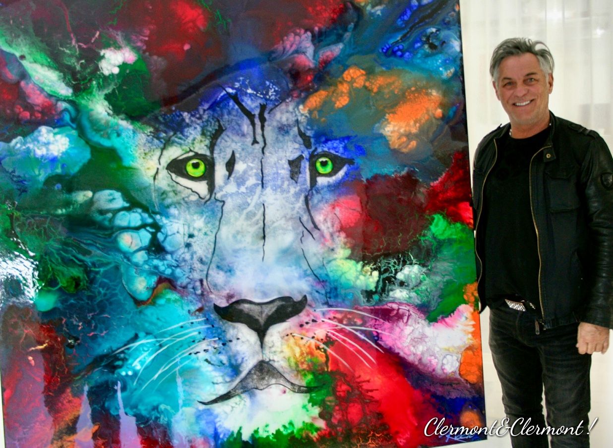 Un homme, Riccio, debout à côté d’une peinture colorée représentant un lion.