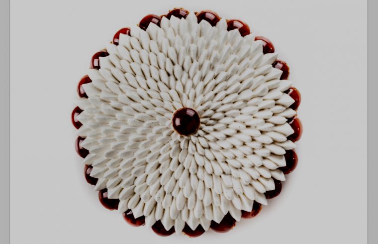 Une broche fleur blanche et rouge sur fond gris.