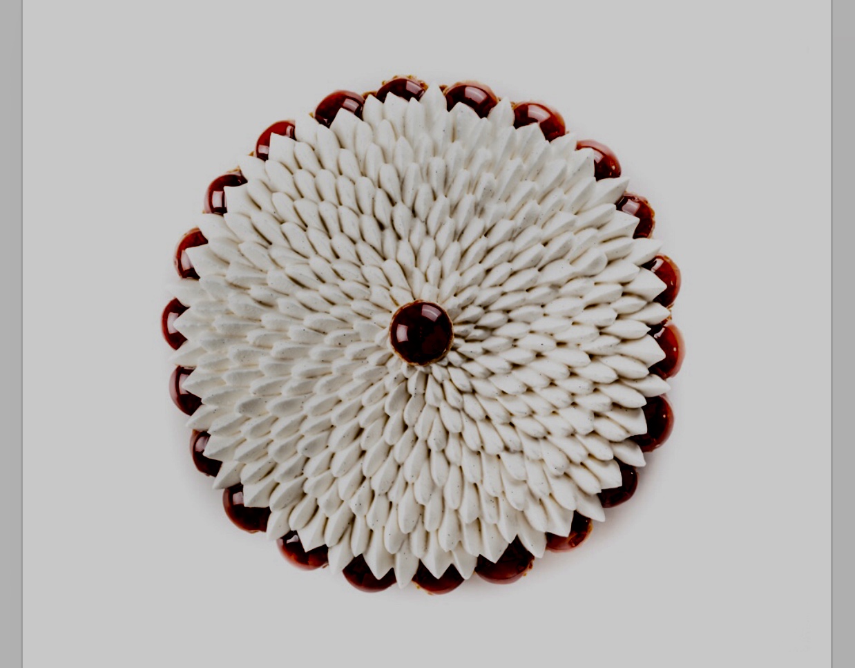 Une broche fleur blanche et rouge sur fond gris.
