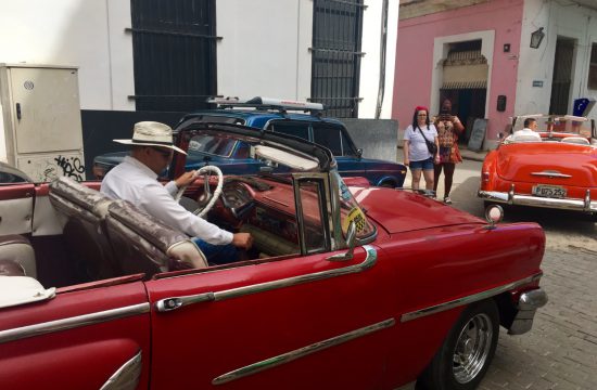 Un homme conduit une voiture classique rouge à travers La Havane.