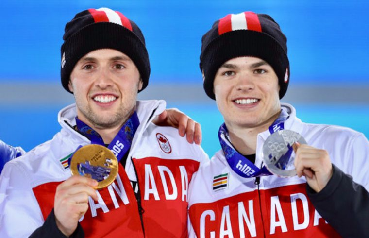 Trois joueurs canadiens de hockey sur glace, Alexandre Bilodeau et Mikaël Kingsbury, posent avec leurs médailles.