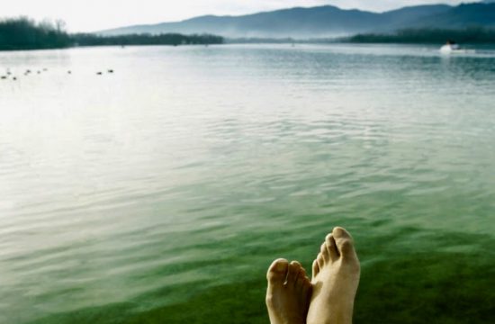Les pieds d'une personne sur un quai surplombant un lac serein, expérimentant le mélange tranquille de spiritualité et d'inspiration créative.