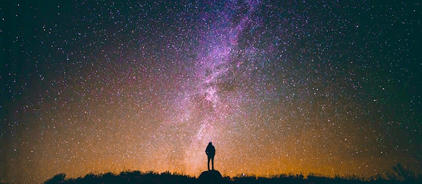 La spiritualité d'une personne se tient sur une colline sous un ciel étoilé.