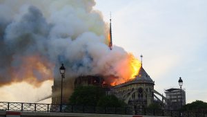 Notre-Dame de Paris, un grand édifice en proie aux flammes, dégage des volutes de fumée en brûlant.