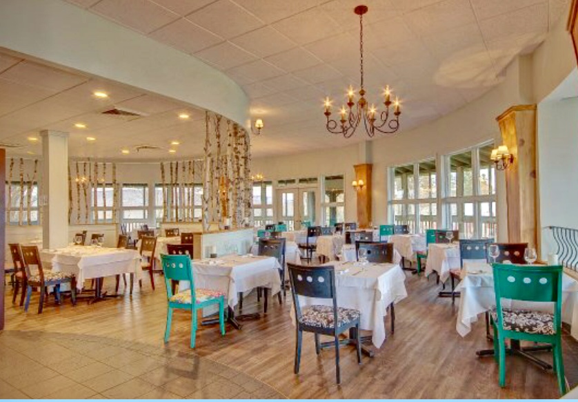L’hôtel Suites Lac Brome, un restaurant avec tables et chaises et lustre.