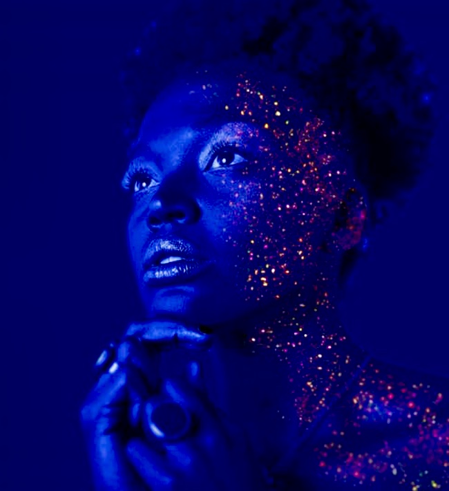 Une femme noire ornée de peinture bleue sur le visage, embrassant l'essence de La spiritualité créatrice.