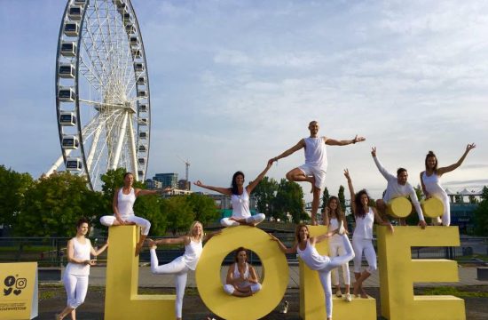 Un groupe de personnes posant devant un panneau jaune avec une grande roue lors de l'événement LOLE White Tour à Montréal.