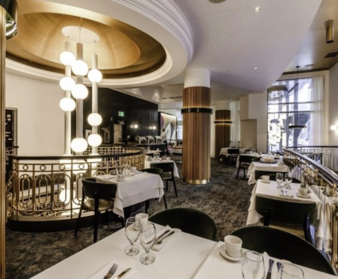L'intérieur du Gustave, un restaurant avec des tables et des chaises blanches.