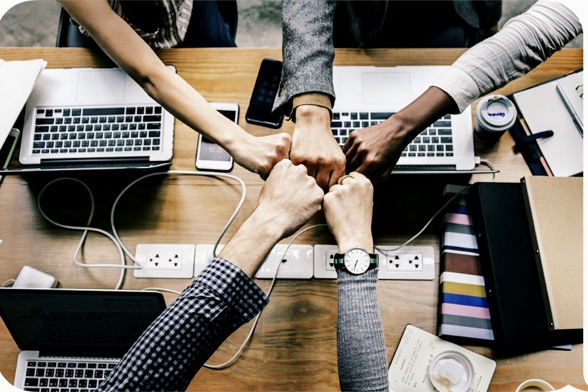 Un exercice de consolidation d’équipe mettant en vedette un groupe de personnes se tenant la main sur un bureau.