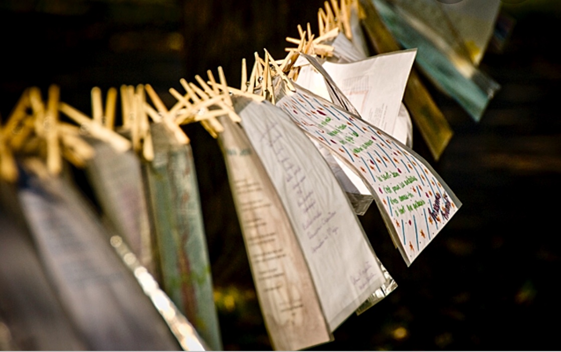 Une ligne de papier suspendue à des pinces à linge, illustrant une mise en scène poétique à Trois-Rivières lors d'une célébration festive.
