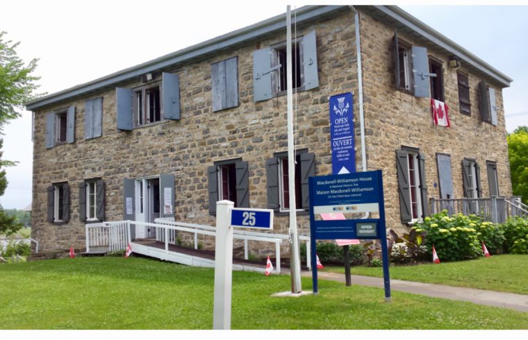 Maison Macdonell-Williamson, un bâtiment en pierre avec des volets bleus et une enseigne.