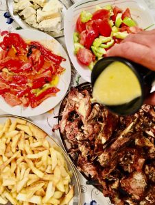 Une personne verse une sauce sur une assiette de nourriture à la manière du Régime méditerranéen.