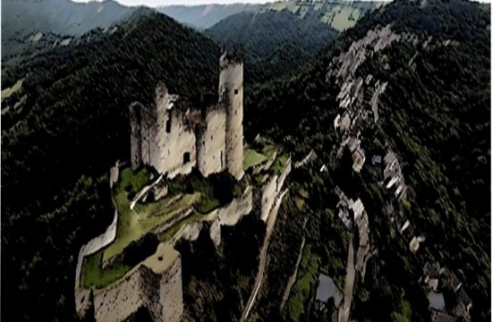 Une vue aérienne d'un château au sommet d'une montagne, entouré de paysages aux contours à couper le souffle.