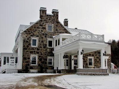 StoneHaven est une grande maison en pierre nichée dans un paysage enneigé serein.
