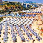 Une plage en Italie avec de nombreux parasols et des gens profitant de la journée ensoleillée.