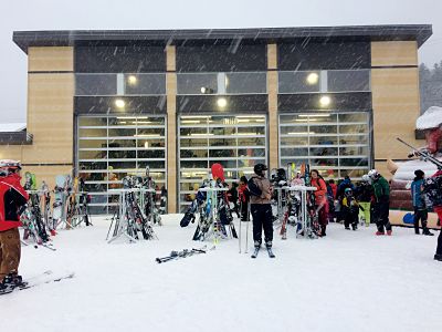 Un groupe de skieurs debout devant un bâtiment dans la neige, prêts à skier.