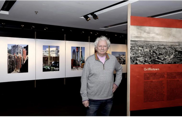Robert Walker, photographe, devant une exposition de photographies.
