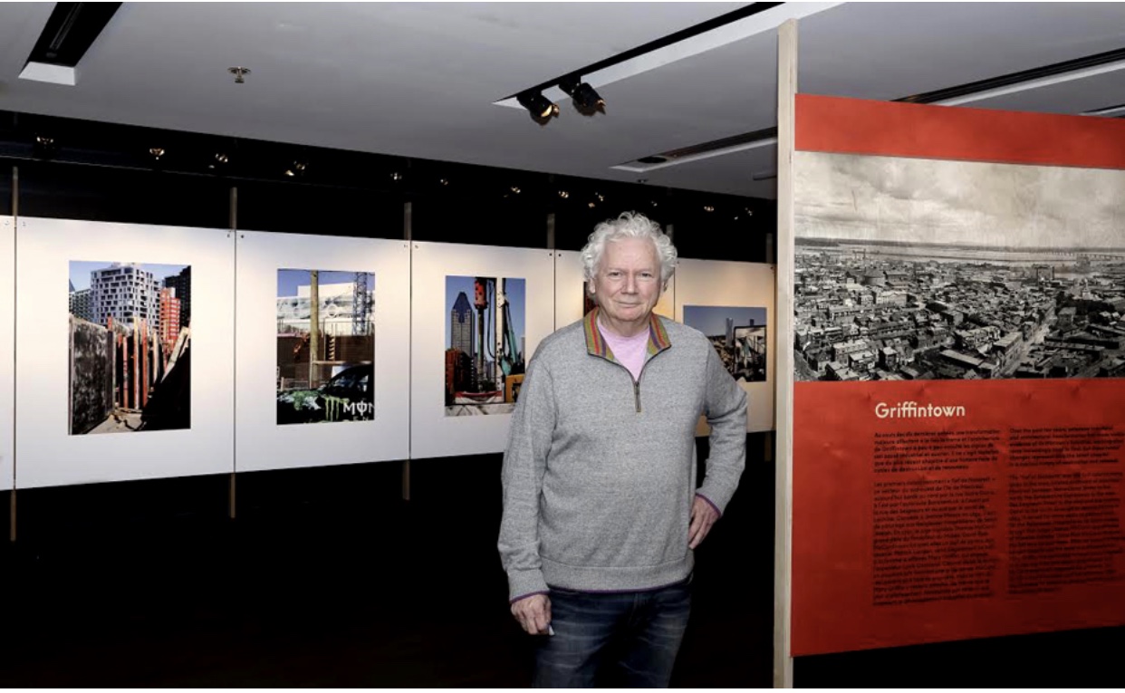 Robert Walker, photographe, devant une exposition de photographies.