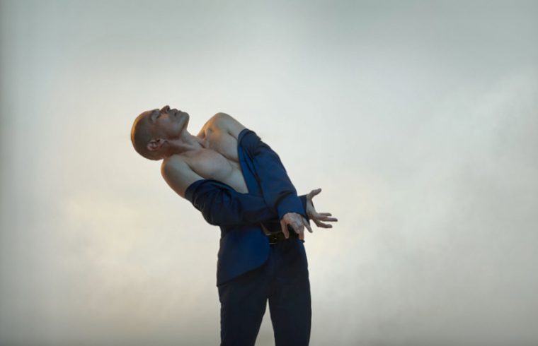 Un homme engagé dans une danse passionnée, se balançant élégamment dans son costume bleu vif, les bras gracieusement tendus.