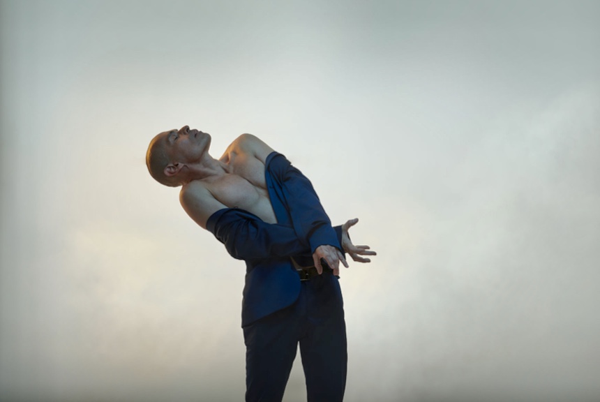 Un homme engagé dans une danse passionnée, se balançant élégamment dans son costume bleu vif, les bras gracieusement tendus.