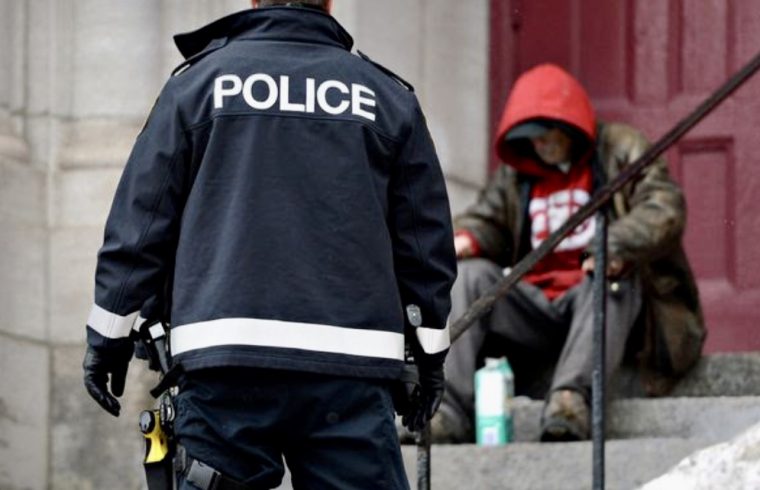 Un policier se tient sur les marches d'un immeuble, assurant la sécurité publique au milieu de la pandémie de COVID-19.