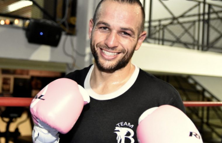 Un homme dans un ring de boxe montrant ses compétences avec des gants de boxe roses.