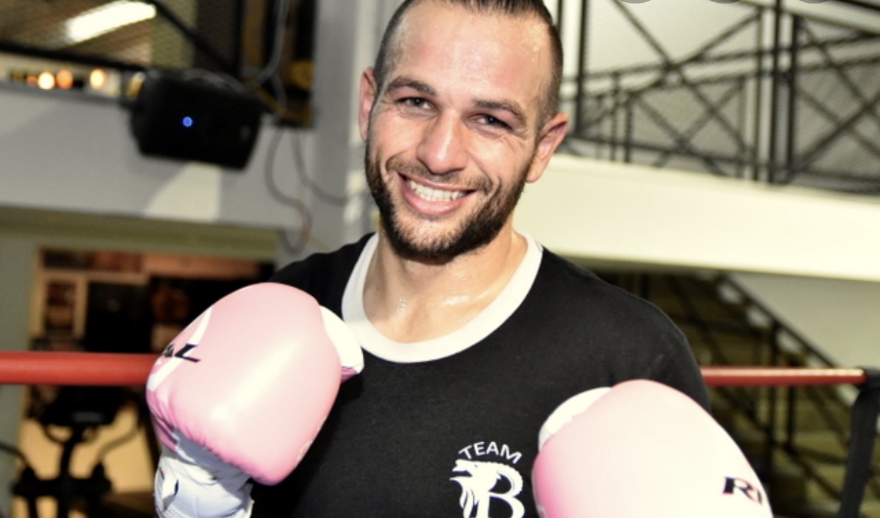 Un homme dans un ring de boxe montrant ses compétences avec des gants de boxe roses.