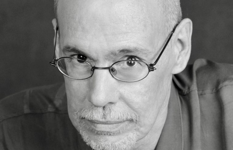 Une photo en noir et blanc d'un homme chauve à lunettes, évoquant la poésie.