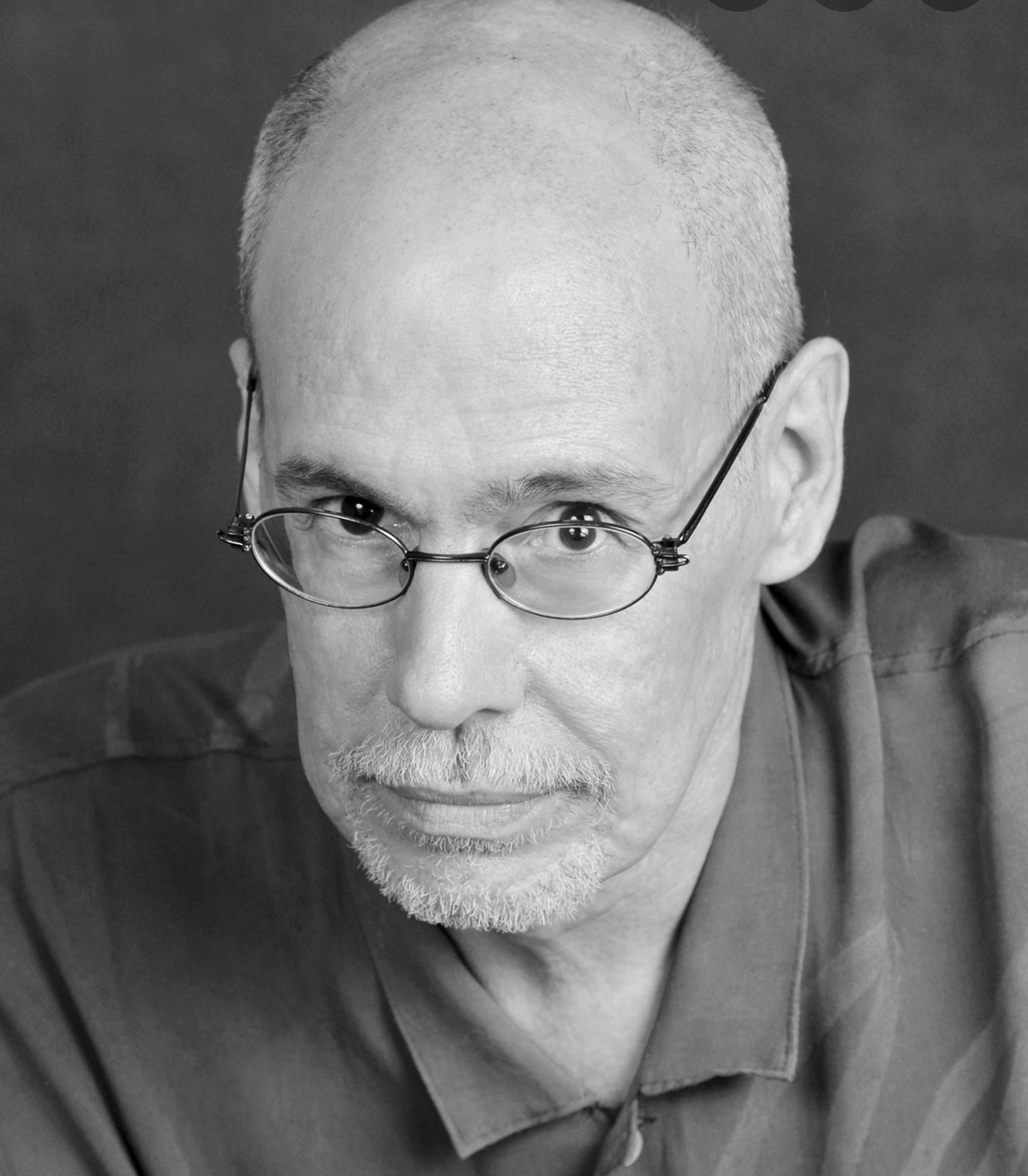 Une photo en noir et blanc d'un homme chauve à lunettes, évoquant la poésie.