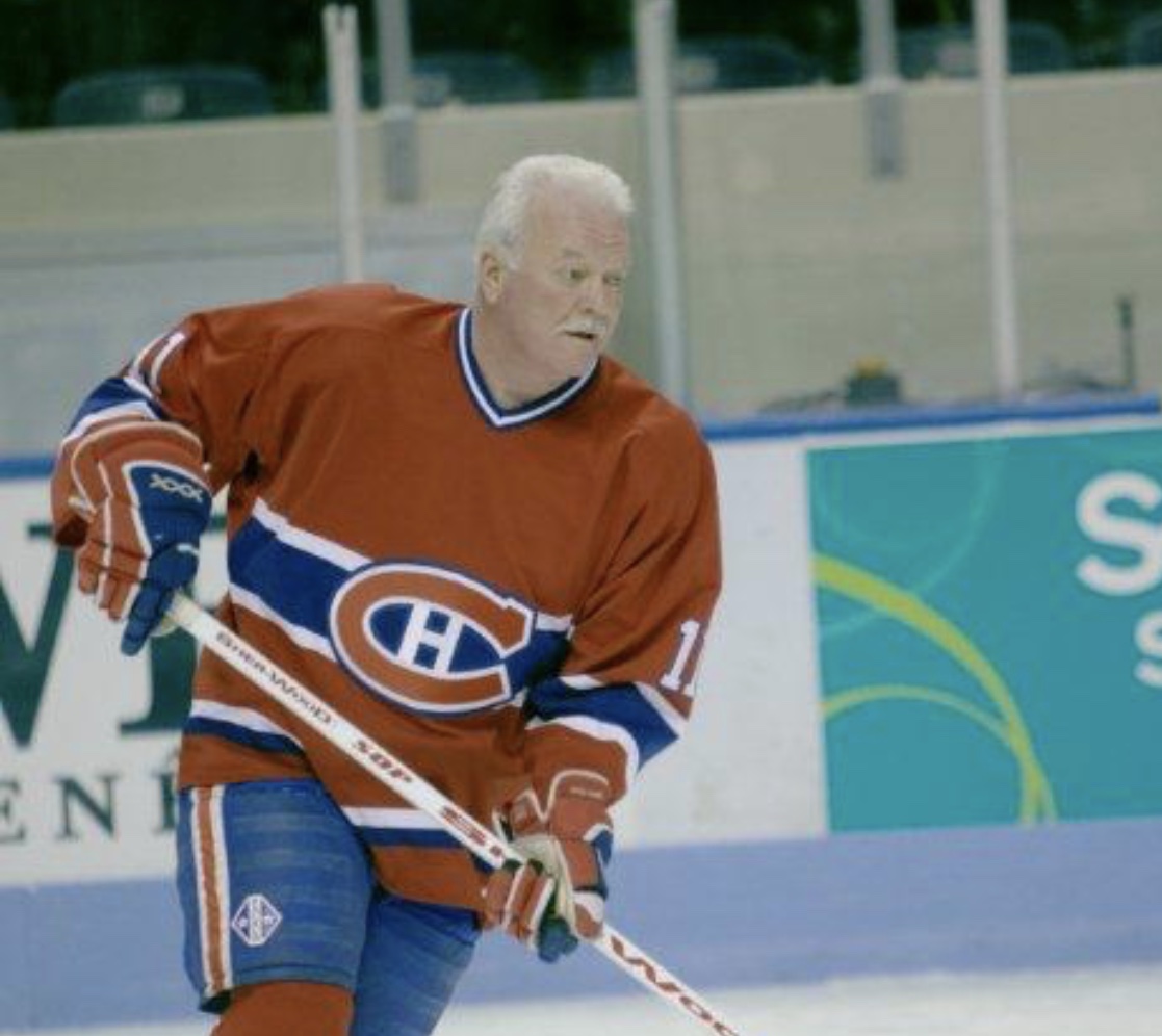 Un homme en maillot rouge joue au hockey sur une patinoire.