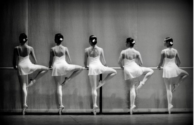 Photo en noir et blanc capturant la grâce exquise d’un groupe de danseurs de ballet.